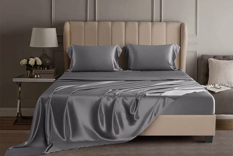 Gray mulberry silk sheet set on a bed in a luxury bedroom setting.