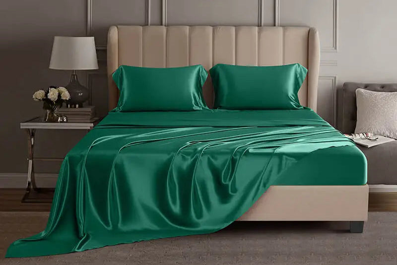 Emerald green mulberry silk sheet set on a bed in a luxury bedroom setting.