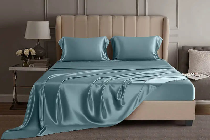 Blue mulberry silk sheet set on a bed in a luxury bedroom setting.