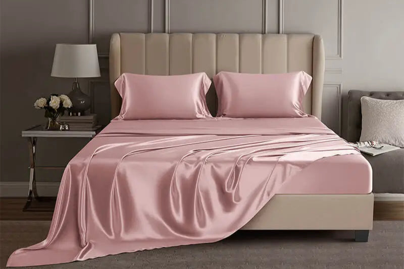 Pink mulberry silk sheet set on a bed in a luxury bedroom setting.
