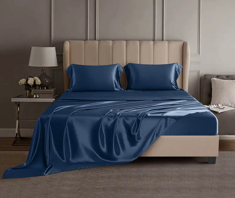 Blue mulberry silk sheet set on a bed in a luxury bedroom setting.