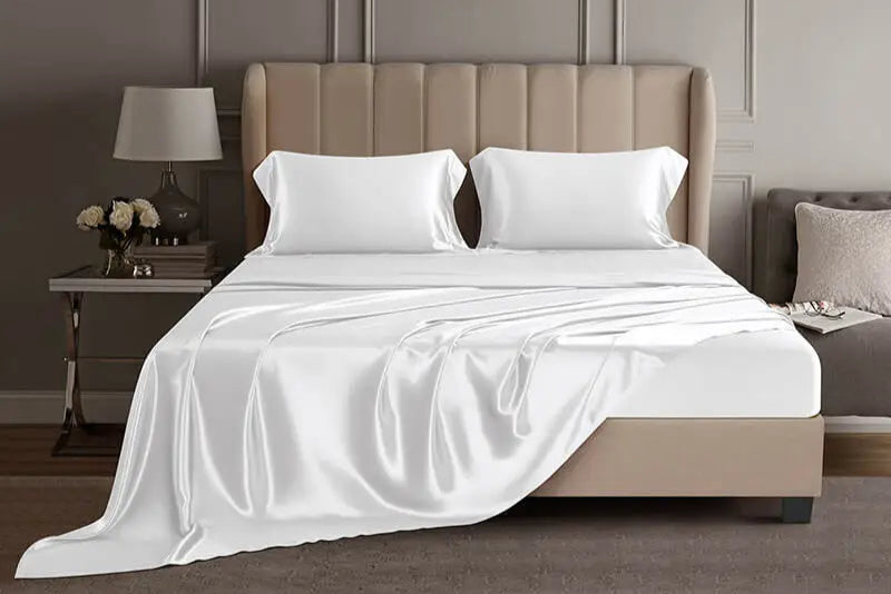 Bed with white mulberry silk sheets and pillows in a luxury bedroom setting