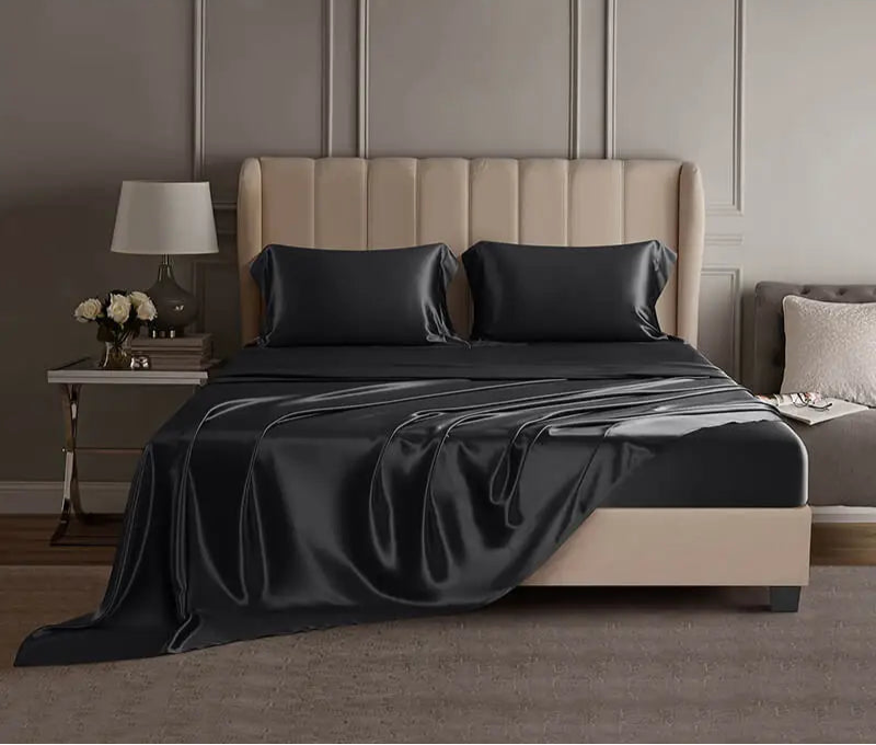Black mulberry silk sheet set on a bed in a luxury bedroom setting.