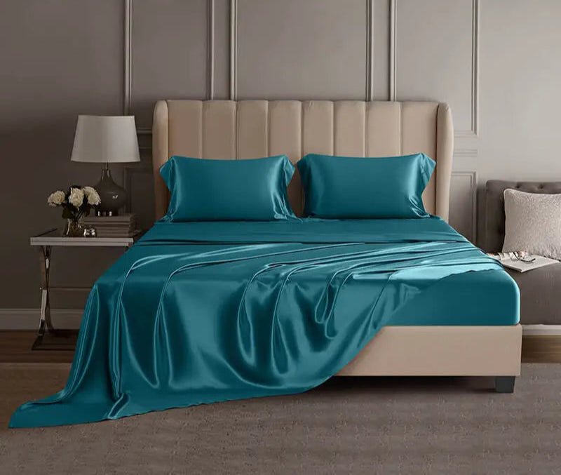 Teal mulberry silk sheet set on a bed in a luxury bedroom setting.