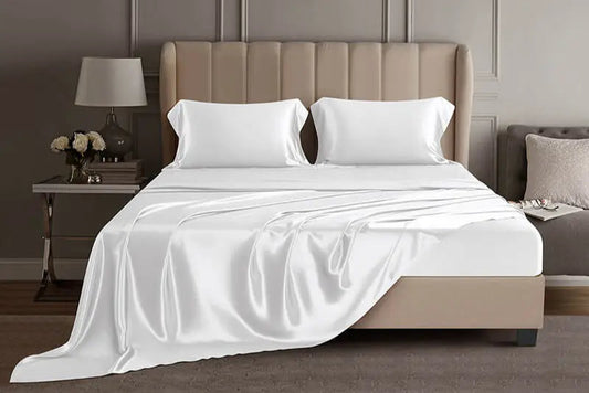 Bed with white mulberry silk sheets and pillows in a luxury bedroom setting